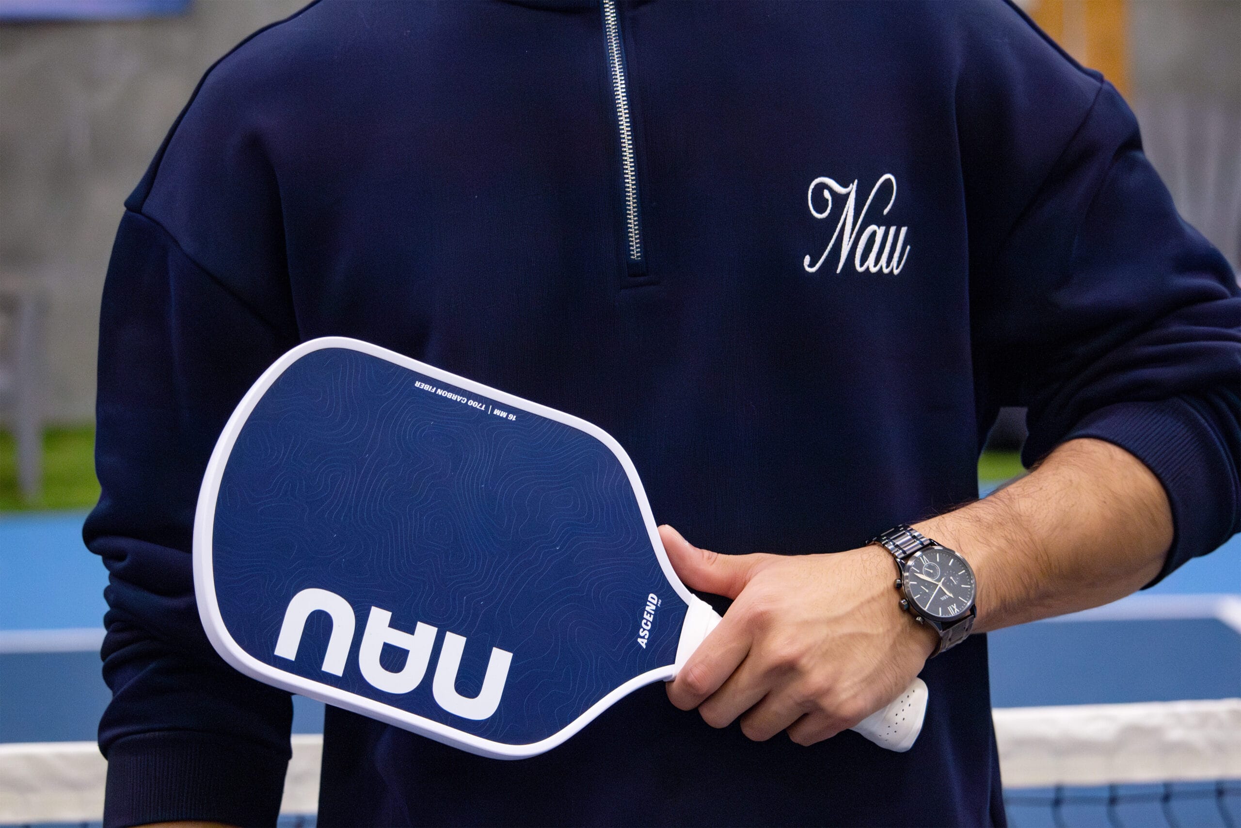Blue ascend pro paddle held up against blue nau sweater